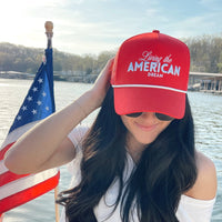 Woman wearing a red cap with 'Living the American Dream' text on a boat with an American flag.