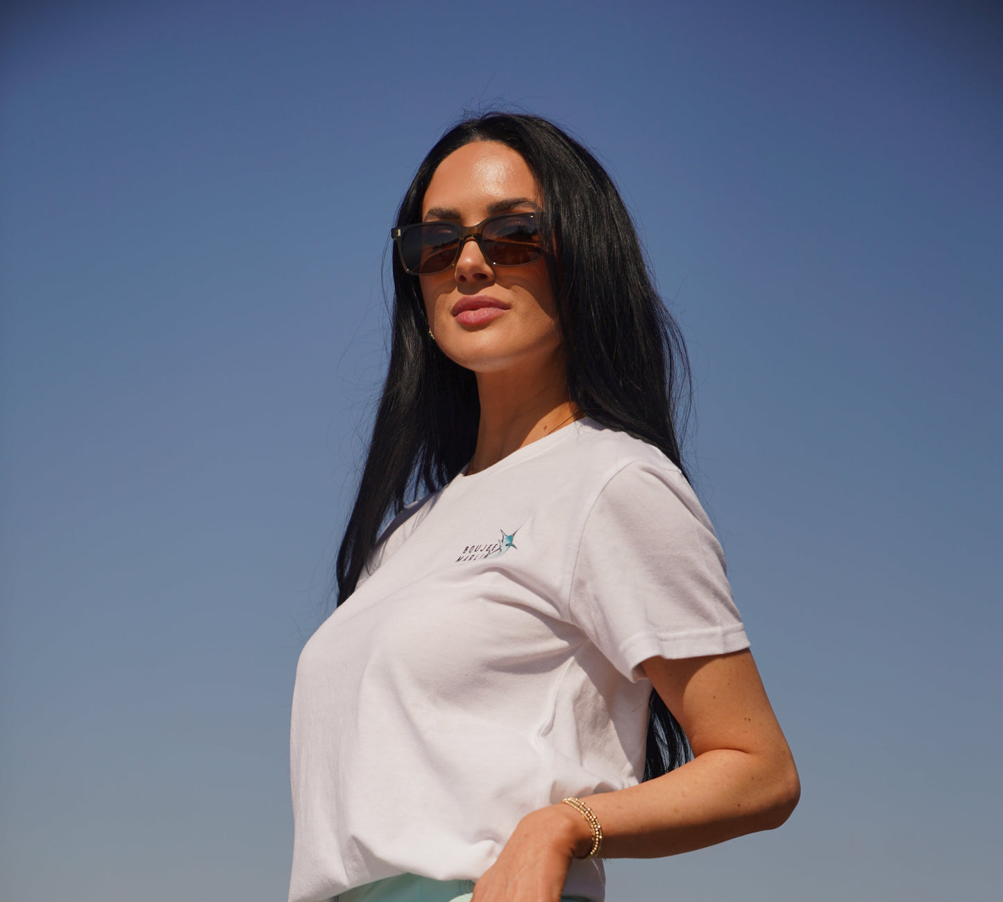 Woman standing outdoors with a clear blue sky and ocean background
