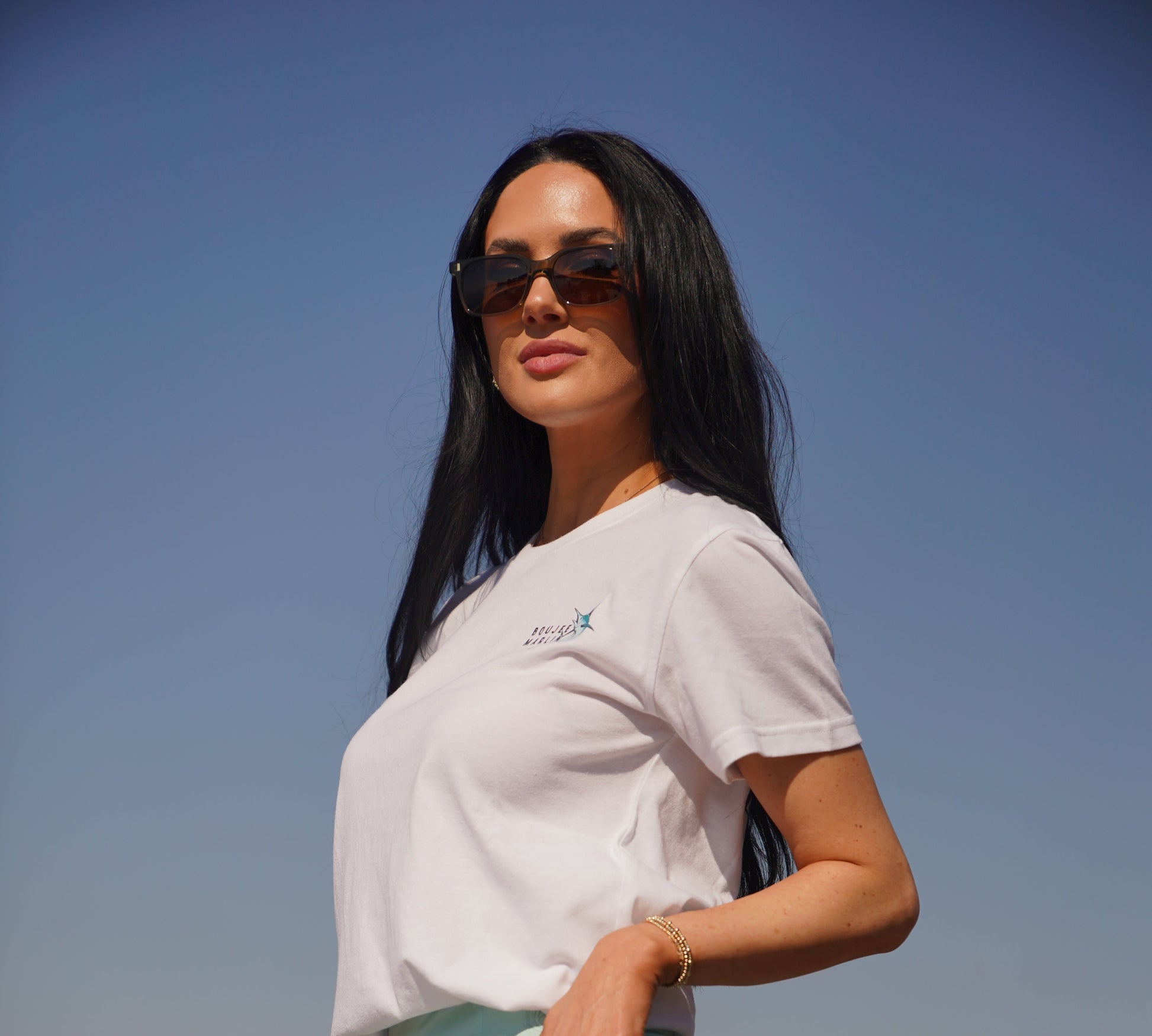 Woman standing outdoors with a clear blue sky and ocean background