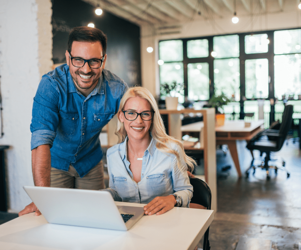 a man and woman smiling at a laptop